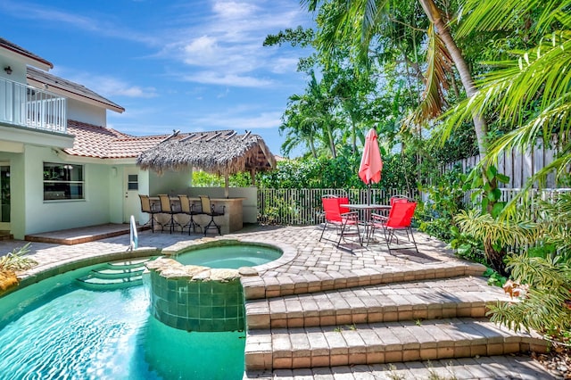 view of pool with a patio, a fenced backyard, a pool with connected hot tub, and outdoor dry bar