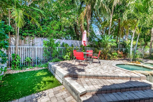 view of patio / terrace featuring an in ground hot tub, outdoor dining area, and a fenced backyard