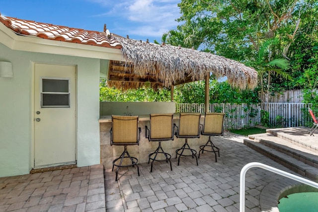 view of patio with outdoor dry bar and fence