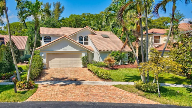 mediterranean / spanish-style house with a tile roof, a front yard, stucco siding, decorative driveway, and a garage