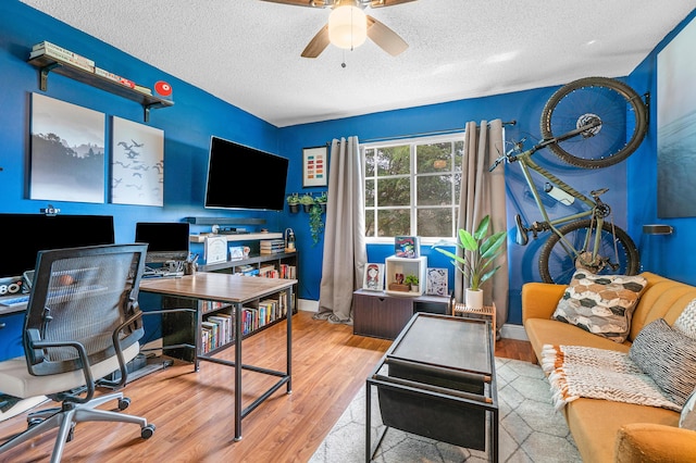 office featuring a textured ceiling, wood finished floors, baseboards, and ceiling fan