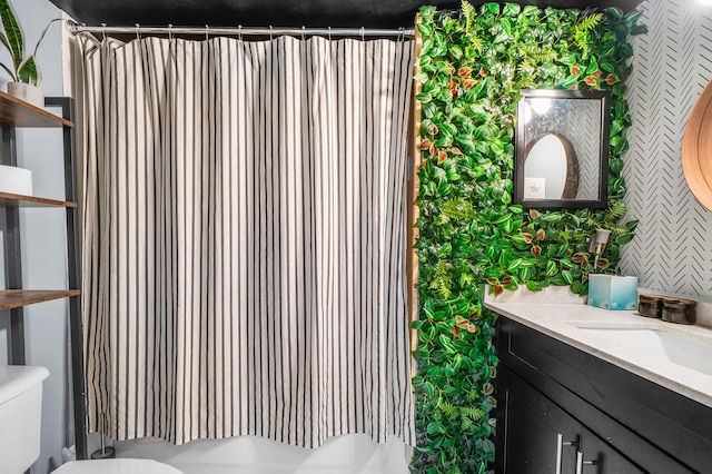 bathroom featuring vanity, toilet, and wallpapered walls