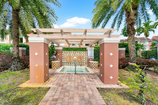 exterior space featuring a community hot tub, a pergola, and fence