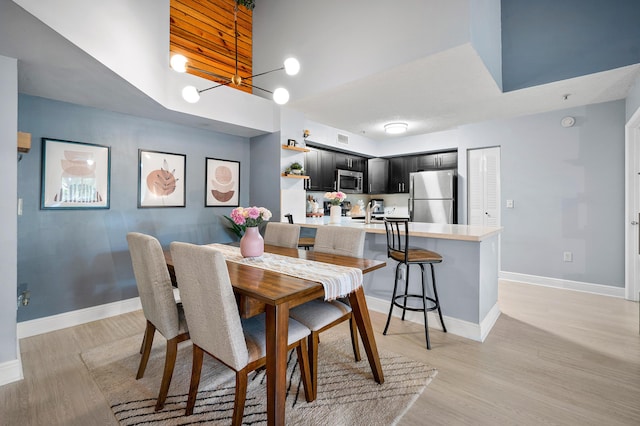 dining room with baseboards, a chandelier, and light wood finished floors