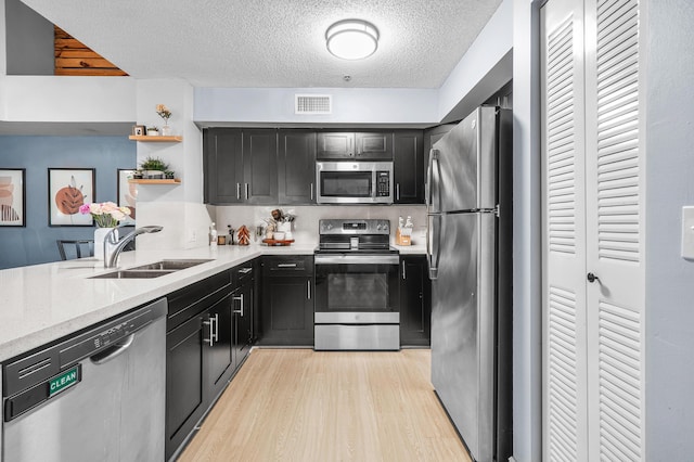 kitchen with dark cabinets, a sink, visible vents, and stainless steel appliances