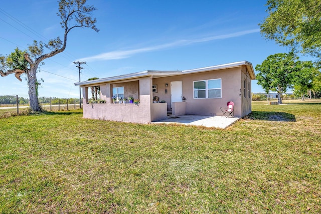 back of property with a patio area, stucco siding, a yard, and fence