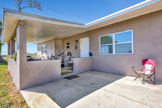 property entrance with stucco siding and a patio