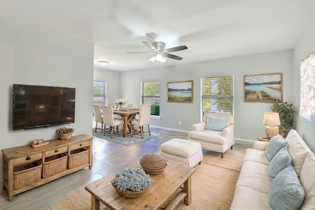 living area featuring visible vents, baseboards, ceiling fan, and wood finished floors