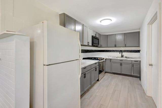 kitchen with electric range, gray cabinets, freestanding refrigerator, a sink, and black microwave