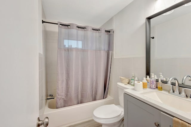 bathroom featuring toilet, vanity, shower / bath combo with shower curtain, and tile walls