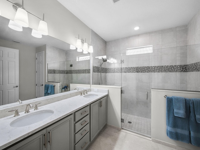 bathroom with a shower stall, tile patterned floors, double vanity, and a sink