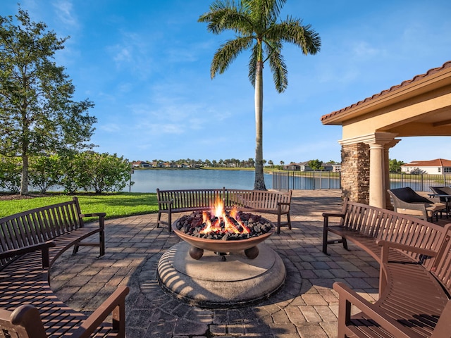 view of patio with a fire pit, a water view, and fence