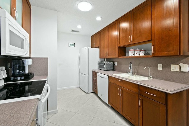 kitchen with visible vents, a sink, tasteful backsplash, white appliances, and light tile patterned flooring