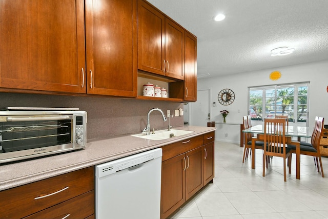 kitchen with a sink, a toaster, white dishwasher, and light countertops