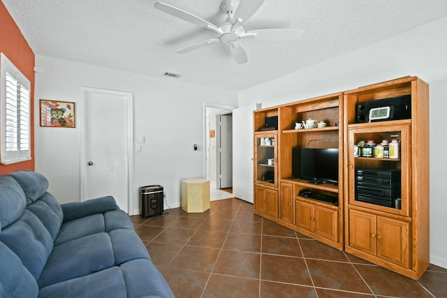 living room with visible vents, a textured ceiling, dark tile patterned floors, and a ceiling fan