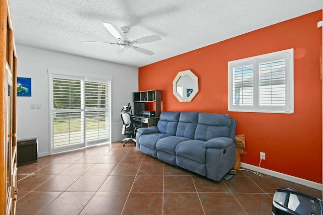 living area with dark tile patterned flooring, a ceiling fan, baseboards, and a textured ceiling