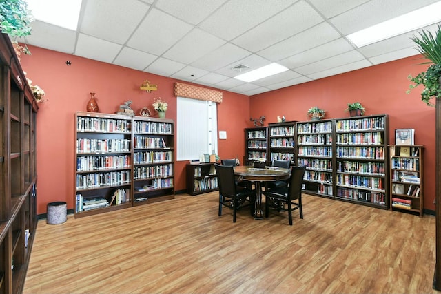 interior space featuring bookshelves, wood finished floors, visible vents, and a drop ceiling