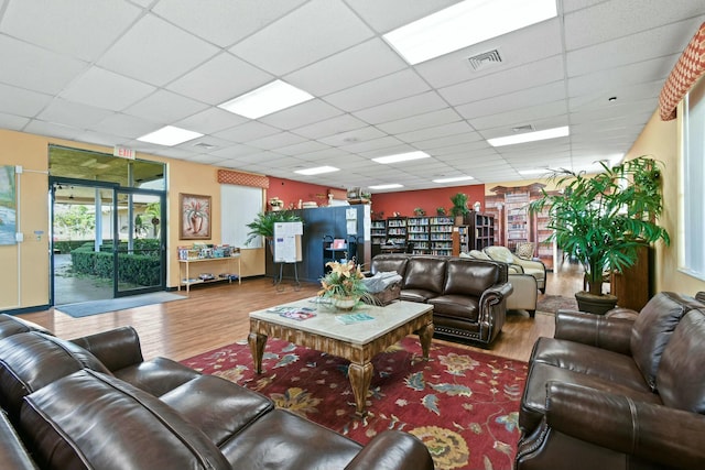 living area featuring wood finished floors, visible vents, and a paneled ceiling