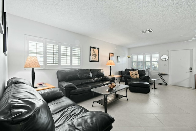 living room featuring light tile patterned floors, visible vents, and a textured ceiling