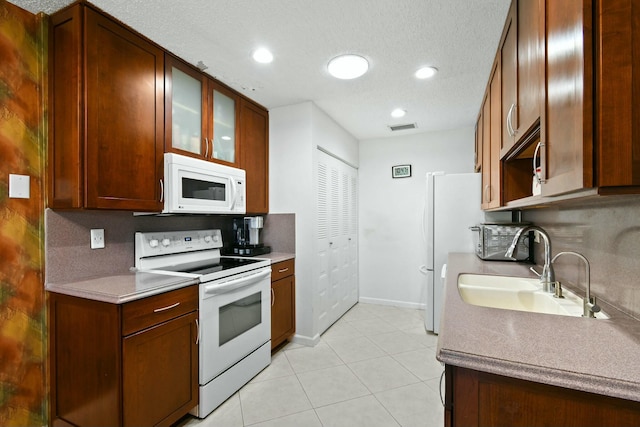 kitchen with visible vents, backsplash, light tile patterned flooring, white appliances, and a sink