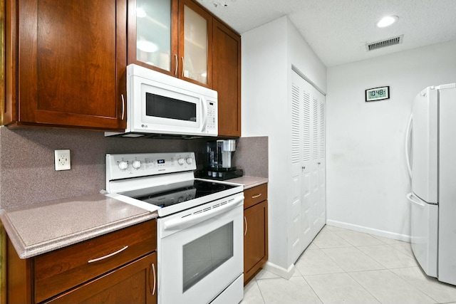 kitchen with white appliances, light tile patterned flooring, visible vents, and backsplash