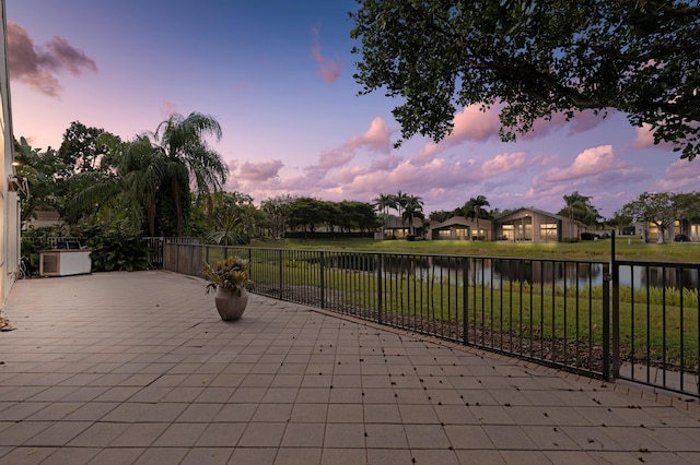 view of patio with a water view and fence