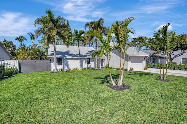 view of front of house featuring a front yard, fence, driveway, stucco siding, and a garage