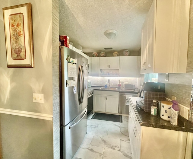 kitchen featuring white cabinetry, decorative backsplash, marble finish floor, a sink, and appliances with stainless steel finishes