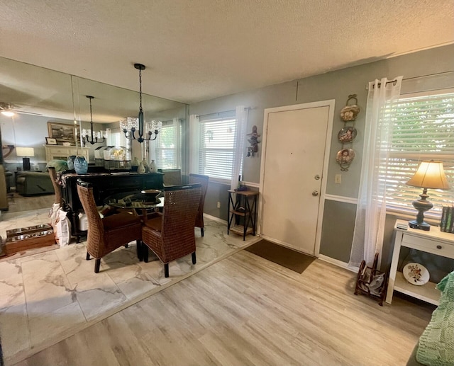 dining room featuring a chandelier, a textured ceiling, baseboards, and wood finished floors