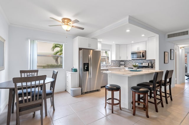 kitchen with tasteful backsplash, visible vents, light countertops, a kitchen breakfast bar, and stainless steel appliances