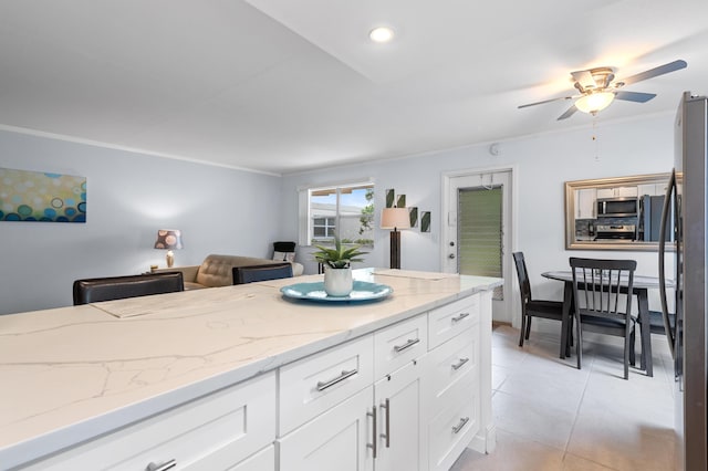 kitchen with light tile patterned floors, a ceiling fan, light stone countertops, stainless steel appliances, and white cabinetry