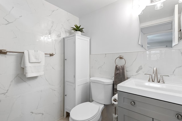 bathroom featuring vanity, tile walls, and toilet