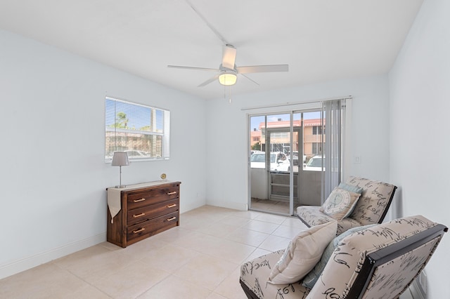 sitting room with light tile patterned floors, baseboards, and ceiling fan