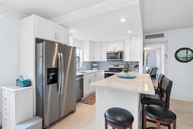 kitchen featuring visible vents, a kitchen breakfast bar, a peninsula, stainless steel appliances, and a sink