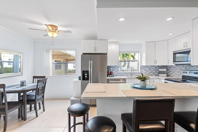 kitchen featuring decorative backsplash, appliances with stainless steel finishes, a breakfast bar area, and a sink