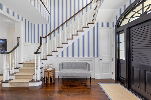 entrance foyer with wallpapered walls, stairs, wainscoting, wood finished floors, and a decorative wall