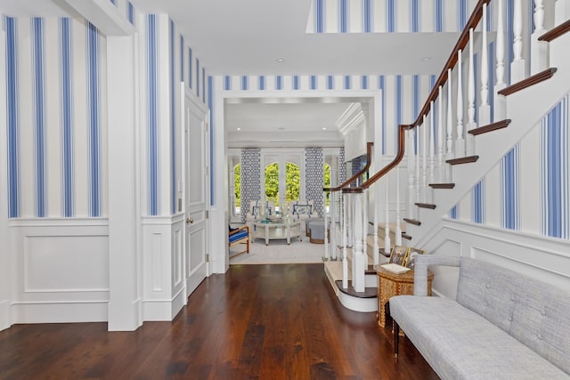 foyer featuring stairway, wood finished floors, and a decorative wall