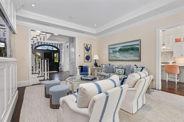 living room featuring stairway, dark wood-style floors, baseboards, visible vents, and ornamental molding