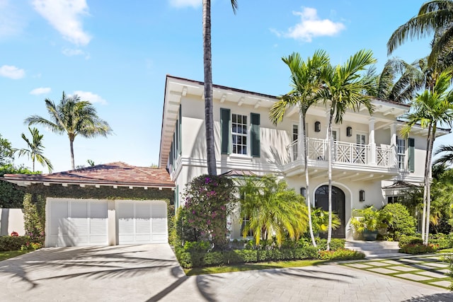 view of front facade with a balcony, an attached garage, driveway, and stucco siding