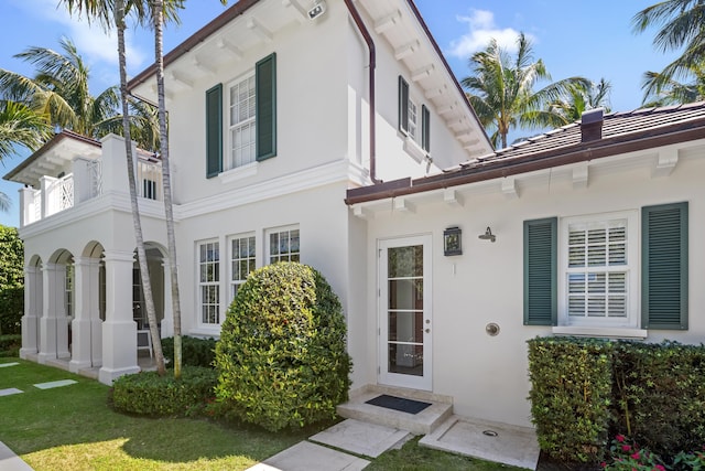 exterior space featuring a tiled roof, a lawn, and stucco siding