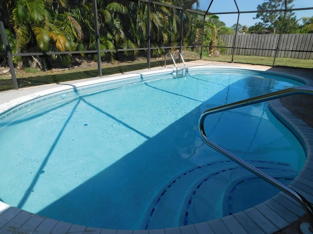 view of swimming pool featuring glass enclosure, a fenced in pool, and fence