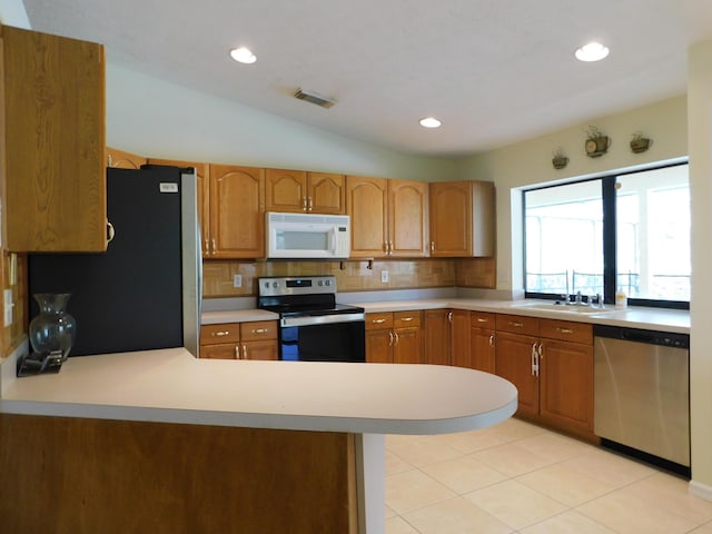 kitchen with tasteful backsplash, light countertops, vaulted ceiling, a peninsula, and stainless steel appliances