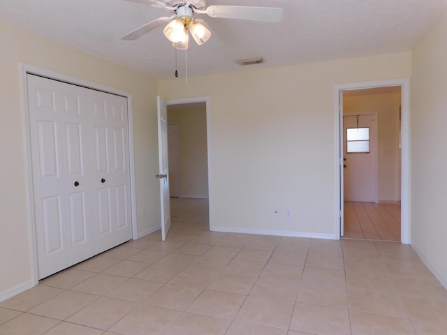 unfurnished bedroom with light tile patterned floors, visible vents, baseboards, and a closet