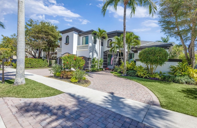 mediterranean / spanish house featuring a front yard, driveway, and stucco siding