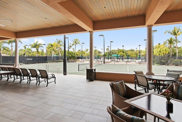 view of patio / terrace featuring a tennis court and fence