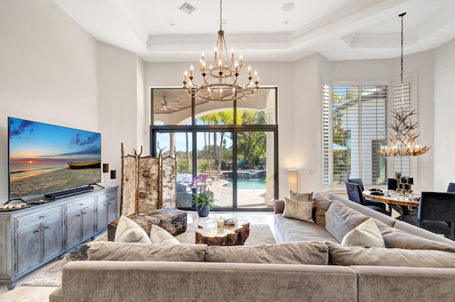 living room featuring a chandelier, visible vents, a high ceiling, and a tray ceiling