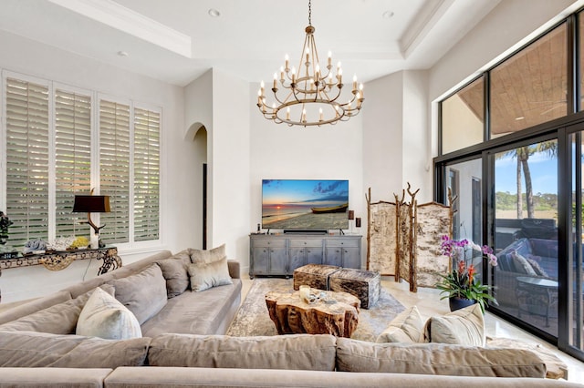 living room with arched walkways, a notable chandelier, crown molding, and a raised ceiling