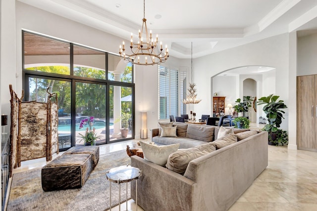 living area featuring arched walkways, a notable chandelier, a raised ceiling, and ornamental molding