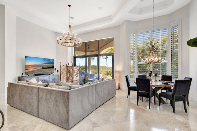 living room featuring a notable chandelier, baseboards, a high ceiling, and a tray ceiling