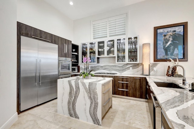 kitchen featuring tasteful backsplash, glass insert cabinets, appliances with stainless steel finishes, modern cabinets, and a sink